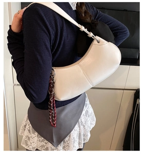 White crescent underarm bag worn by model showing side profile and woven knot detail