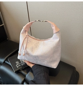 Detail of light pink hobo bag with delicate butterfly embroidery and metal buckle closure