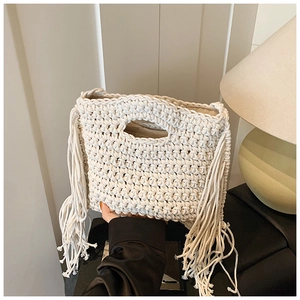 Detail of cream knit handbag featuring thick bohemian fringe and circular hollow handle
