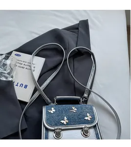 Close-up of silver leather handbag with blue denim flap and metal butterfly details
