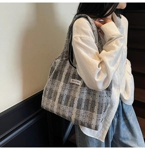Détail d'un grand sac cabas en toile à carreaux gris avec étiquette sur l'épaule