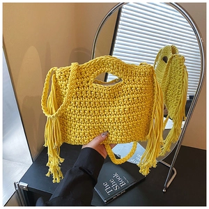 Detail of yellow hand-woven knit tote bag with fringes and braided handles in boho style