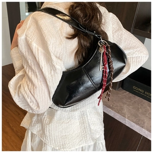 Close-up of black patent leather crescent shoulder bag with metallic key pendant details