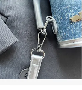 Detailed close-up of blue denim bag featuring silver bird logo and sturdy metal swivel hook