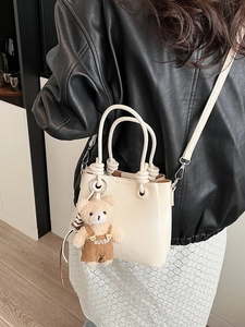 Chic beige lychee leather bucket bag with cute bear charm and adjustable shoulder strap