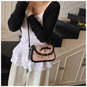 Detail of pink pleated crossbody bag with black bows and a heart-shaped metal charm