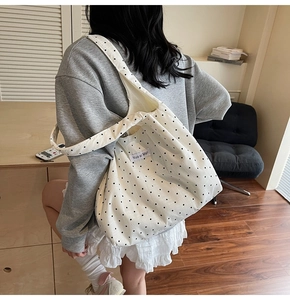 Détail du sac cabas en toile blanche à pois noirs avec étiquette de marque sur le côté