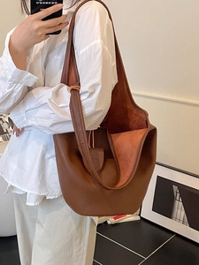 Brown lychee leather bucket bag with minimalist design for women, shown in professional styling