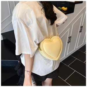 Détail du sac à bandoulière en forme de cœur en cuir jaune pâle avec chaîne dorée