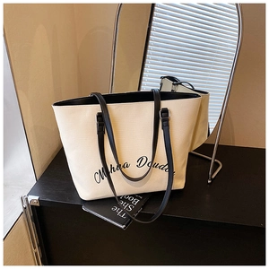 Dettaglio della borsa tote in tela con manici in pelle nera e scritte artistiche eleganti