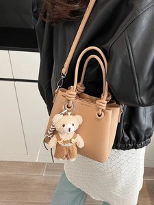 Chic beige lychee leather bucket bag with knotted handle and cute teddy bear pendant