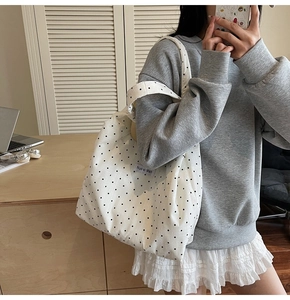 Vue détaillée du grand sac cabas en toile blanche à pois noirs porté par un mannequin