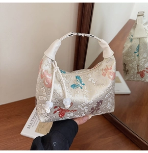 Detail of embroidered canvas bag with traditional dragon patterns and white tassel decor