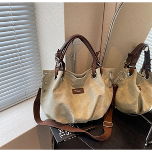 Detailed close-up of canvas tote bag with brown leather accents and metal eyelet design
