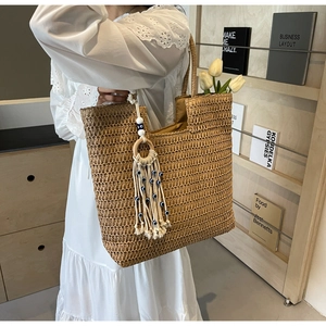 Straw woven tote bag with a tassel charm featuring blue evil eye beads for women
