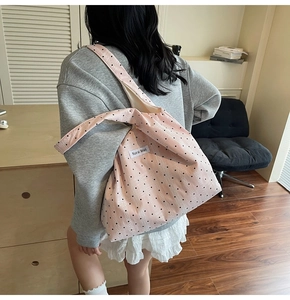 Gros plan du sac cabas en toile rose à pois avec une étiquette de marque brodée