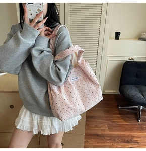 Gros plan d'un sac cabas en toile rose à pois avec étiquette tissée et bandoulière large