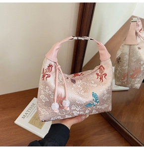 Detail view of embroidered pink satin tote bag with traditional fish and butterfly patterns