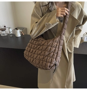 Close-up of brown quilted nylon tote bag worn by a model in a cafe setting