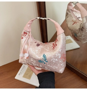 Detailed close-up of pink satin dumpling bag featuring intricate traditional embroidery