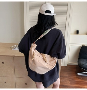 Beige nylon crescent bag with ethnic embroidered strap shown on model's shoulder