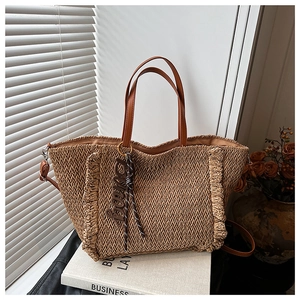 Close-up of brown straw woven tote bag featuring ruffled edges and leather straps
