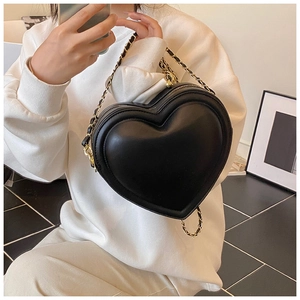 Dettagli di un'elegante borsa a tracolla nera a forma di cuore con catena d'oro