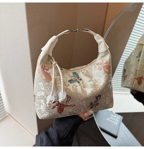 Detailed embroidery of butterflies and clouds on a silk dumpling bag with pearl charms
