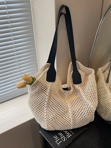 Sac fourre-tout en crochet crème avec bandoulières en cuir noir sur surface noire