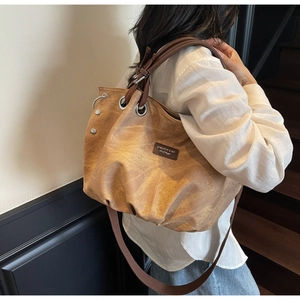 Detail view of a retro brown canvas tote bag with leather straps on a model's shoulder