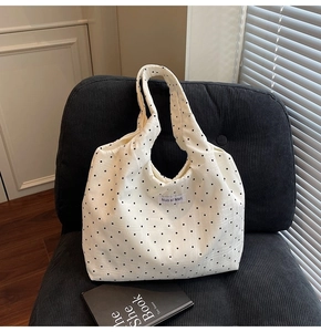 Gros plan détaillé sur la texture du sac cabas en toile à pois blancs et étiquette logo