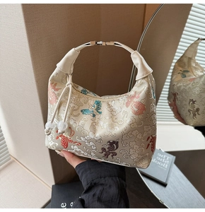 Close-up of embroidered butterfly and goldfish motifs on a satin dumpling bag with silk tassel