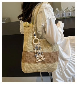 Detail of woven straw tote bag featuring contrast colors and stylish tassel with blue eye charm