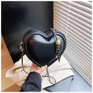 Dettaglio borsa a cuore in pelle nera con tracolla a catena dorata e sfera di regolazione