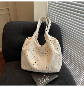 Détail du sac cabas en toile à pois blancs avec texture et étiquette de marque