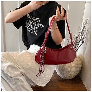 Detail of burgundy patent leather baguette bag with woven rope charm on a model