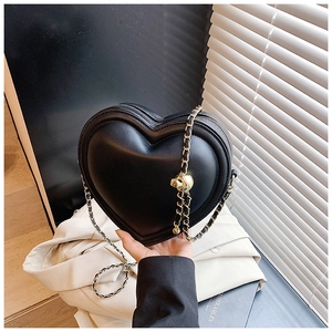 Dettaglio borsa a cuore nera in pelle con catena dorata e sfera metallica decorativa
