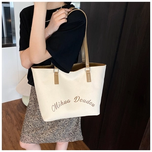 Dettaglio borsa tote in tela bianco sporco con manici in pelle marrone e scritta Mihua