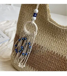 Detail of straw tote bag with fringe tassel, wooden ring and evil eye bead decoration