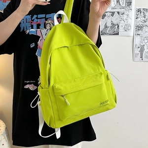Dettaglio di zaino in nylon verde neon con spallacci bianchi e tasca laterale