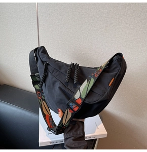 Detail of black nylon crescent bag featuring a bohemian floral embroidered wide strap