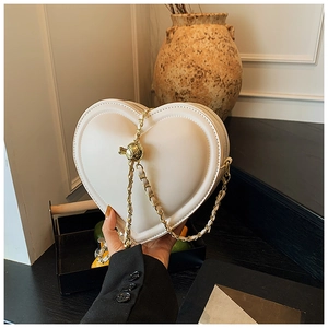 Dettaglio borsa a tracolla a cuore bianco crema con catena dorata e sfera in metallo regolabile