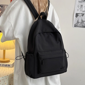 Dettaglio di uno zaino nero in nylon con tasca frontale a zip e tasche laterali per il viaggio