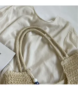 Detailed close-up of beige woven tote bag texture with beaded tassel and rope handles