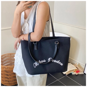 Detail of black canvas tote bag with white embroidery and sturdy double handles