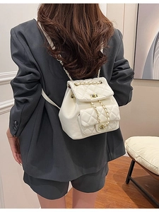 Chic beige quilted mini backpack with gold chain straps on a model in gray blazer