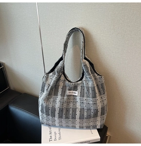 Détail du sac cabas en toile à carreaux gris avec pois noirs sur un canapé moderne
