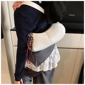 White semi-circle shoulder bag with woven pendant detail worn by a model in a modern room