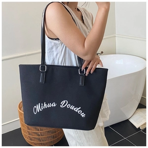 Détail d'un grand sac cabas en toile noire avec lettrage blanc et doubles bandoulières