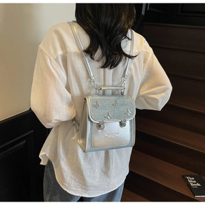 Rear view of a model wearing the silver mini backpack with a 3D butterfly design